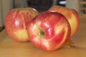 Three apples on the plank table