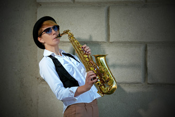 Girl with saxophone outside near the brick wall