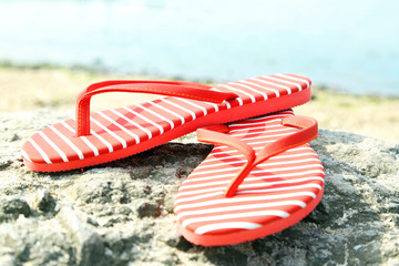 Bright flip-flops on stone, nature background
