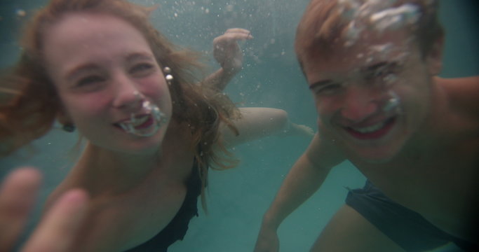 Couple smiling while swimming underwater in a pool