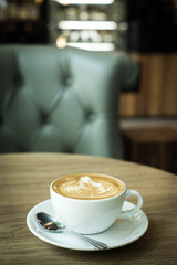 Hot latte art coffee cup on wooden table, vintage and retro styl
