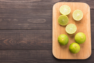 Fresh limes on cutting board on wooden background