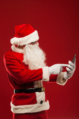Modern Santa Claus using tablet pc over red background