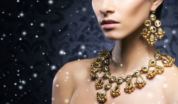 Young, beautiful and rich woman in jewels of gold and stones ove