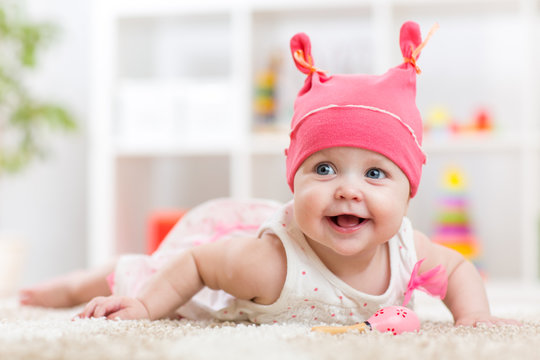 Cute baby in hat on the bed having fun