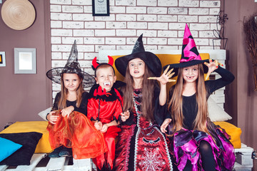 Boys and girls, dressed up in Halloween costumes, show emotions of witches and vampires. Halloween party with group children.