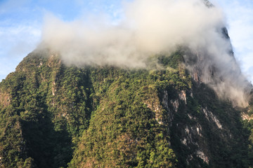 Top of mountains covered by clouds and fog in the morning of the sunny day.