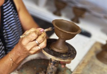 Woman's hands in processing earthen vessel on the potter's wheel