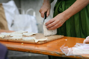 Frau im Dirndl schneidet Käse in Scheiben