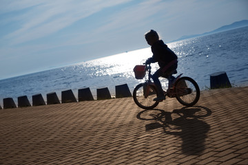 Girl on bike on the seafront promenade at sunset
