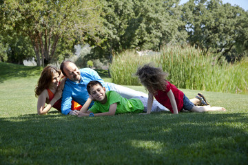 Happy family is lying down on the grass at park