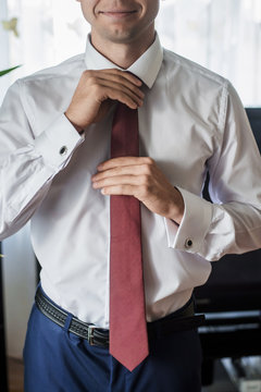 Close-up fragment of a man in a business suit correcting his tie