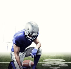 Fototapeta premium American football player kneeling while holding ball