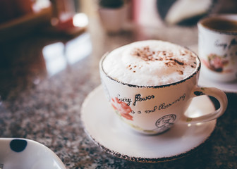 Cappuccino coffee cup on a table. Vintage retro style photo with color filters, vignette effect,...