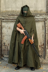 a man in a military coat and a balaclava aiming a machine gun of Kalashnikov RPK
