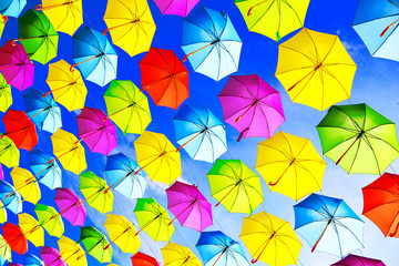 Fototapeta na wymiar Colorful umbrellas urban street decoration. Hanging Multicolored umbrellas over blue sky