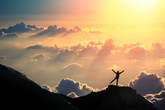 The joy of life. A person is standing on the top of the mountain above the clouds. 