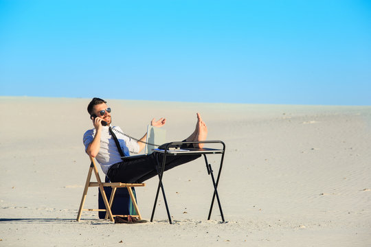 Businessman using  laptop in a desert - Powered by Adobe