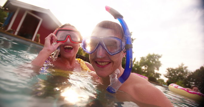 Girlfriend playfully trying to dunk boyfriend in pool with snorkels