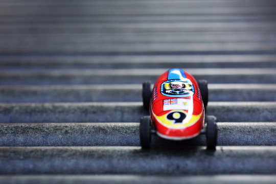 An antique race car, made before 1960s, parks on the metal pipes of playground slide.