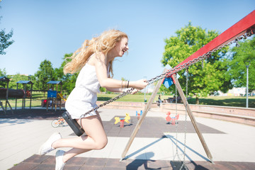 Side view of smiling woman enjoying swing