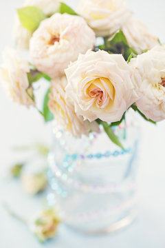 Beautiful fresh roses in a vase on a table . light background .