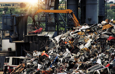 Eco Friendly car Recycling. Crane lifting flattened cars out of stack of obsolete cars in recycling...