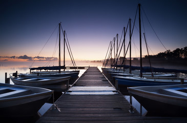 Obraz premium pier and yacht on lake at sunrise