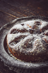 Cake with icing sugar on the dark wooden table with lace napkin