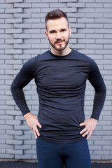 Smiling male runner in  t-shirt  standing against cement wall background