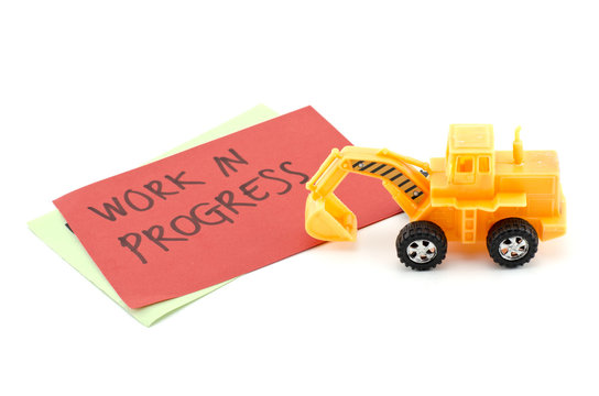 image concept yellow toy bulldozer with on color paper and blur word work in progress. isolated white background