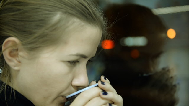 City, showcase glass. Depressed woman drinking tea by the window in home 