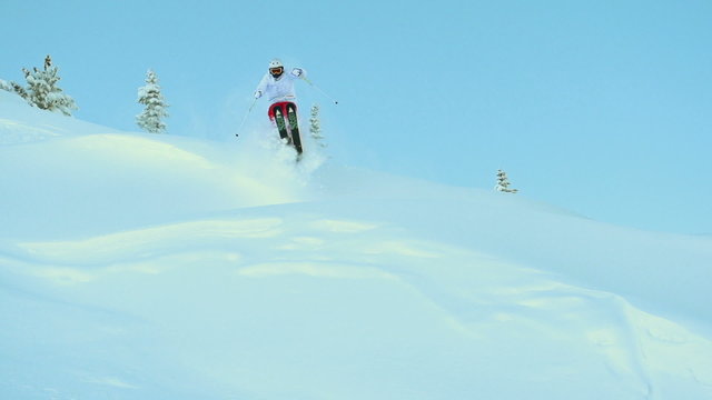 Mountain skier jumping in fresh snow powder and riding down the slope