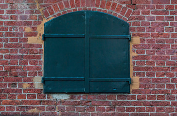 Red brick wall against window closed in middle frame.