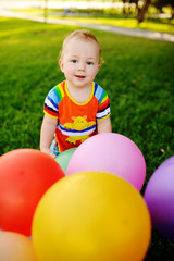 Obraz premium baby boy with colored balloons on a background of grass