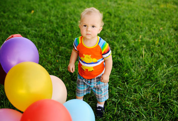baby boy with colored balloons on a background of grass