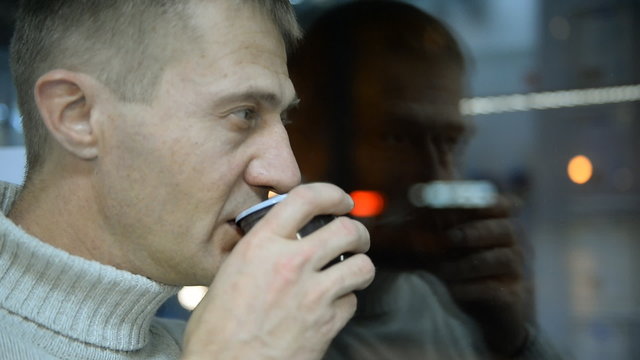 Depressed man drinking tea by the window in home 