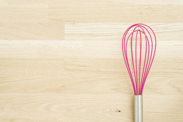 Pink whire wisk on wooden kitchen table