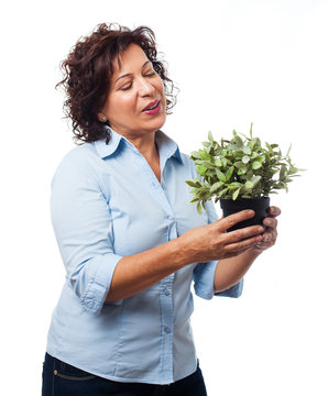 portrait of a mature woman holding a plant on a white background