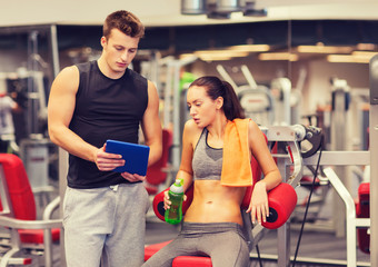 smiling young woman with personal trainer in gym