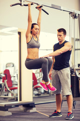 Fototapeta premium young woman with trainer doing leg raises in gym