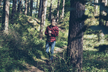 Man with beard walking on forest trail.