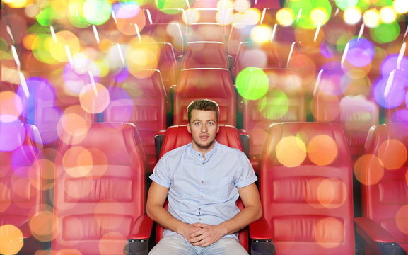 happy young man watching movie in theater