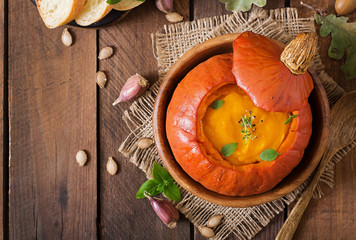 Pumpkin cream soup with peppers and herbs in a pumpkin. Top view
