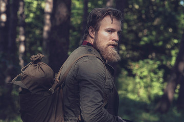 Side view of backpacker with beard in forest.
