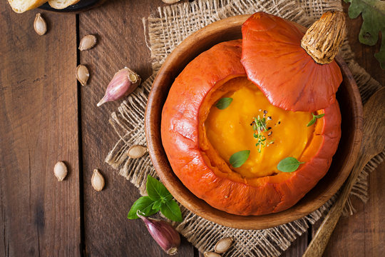 Pumpkin cream soup with peppers and herbs in a pumpkin. Top view