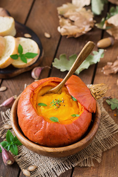 Pumpkin cream soup with peppers and herbs in a pumpkin