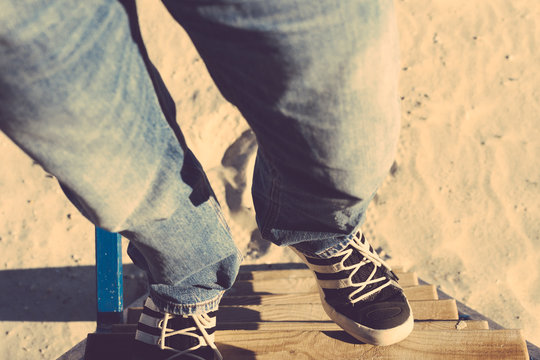Male legs in jeans and sneakers going up the stairs