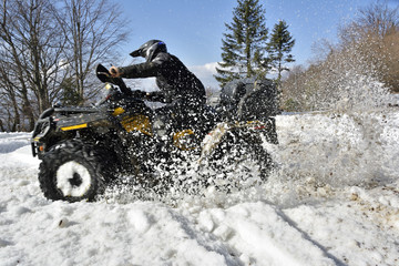 man driving a quad bike in the winter field