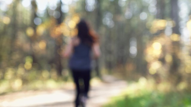 Young woman jogging with stopwatch in the forest